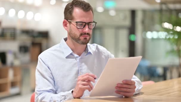 Разочарованный бизнесмен читает документы в офисе — стоковое видео