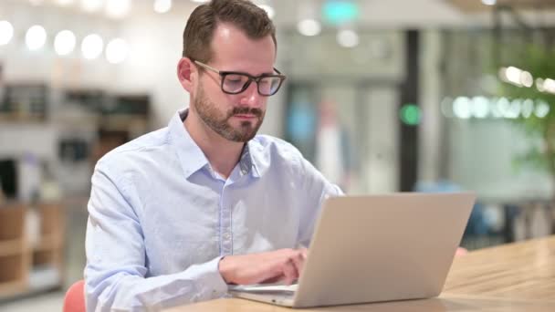 Empresário com laptop sorrindo para a câmera no escritório — Vídeo de Stock