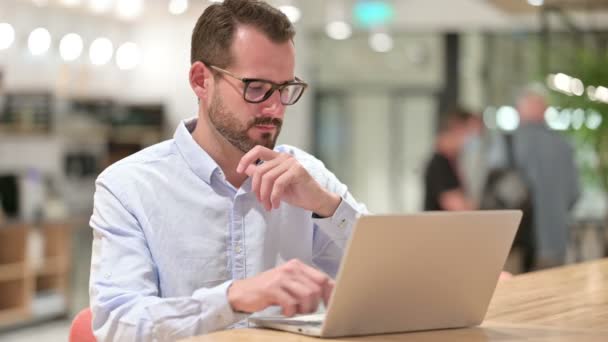 Pensiv affärsman tänker och arbetar på laptop i Office — Stockvideo