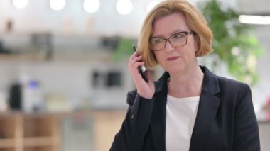 Akıllı telefondan konuşan neşeli, yaşlı iş kadınının portresi