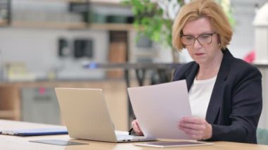Laptop ve Belgeler üzerinde çalışan Odaklanmış Eski İş Kadını 