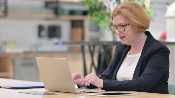 Старая деловая женщина делает видеозвонок на ноутбуке в офисе — стоковое видео
