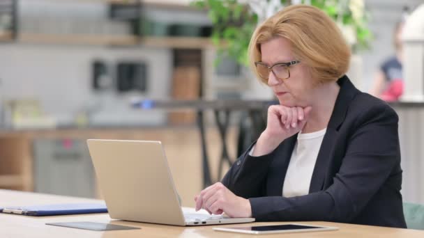 Vecchia imprenditrice che pensa e lavora al computer portatile in ufficio — Video Stock