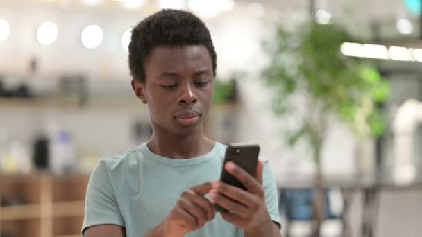 Portret van de jonge Afrikaanse man met verlies op de smartphone — Stockvideo