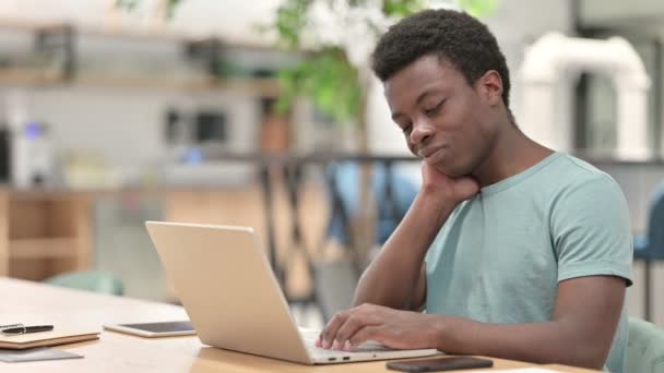 Fatigué jeune homme africain avec ordinateur portable ayant mal au cou — Video