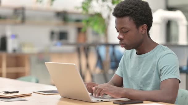 Молодой африканский человек работает на ноутбуке, печатает — стоковое видео