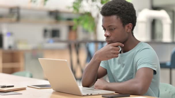 Pensive Mladý Afričan myšlení a práce na notebooku — Stock video