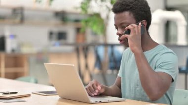 Akıllı telefon ve dizüstü bilgisayar kullanan genç bir Afrikalı.