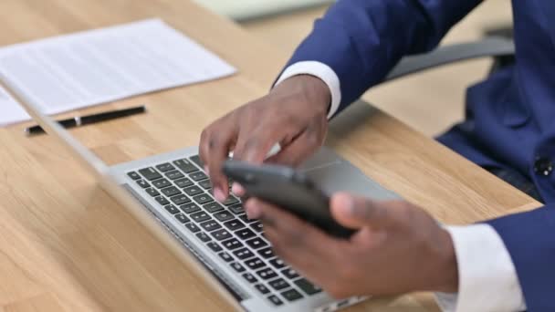 Zbliżenie African Businessman za pomocą smartfona i laptopa — Wideo stockowe