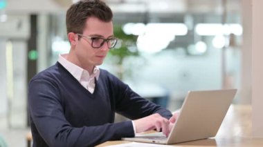Ofiste Dizüstü bilgisayarda çalışan genç iş adamı.