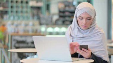 Akıllı telefon ve dizüstü bilgisayarla çalışan Arap Kadın