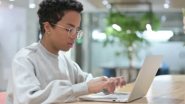 Lässige Afrikanerin mit Laptop lächelt in die Kamera — Stockvideo