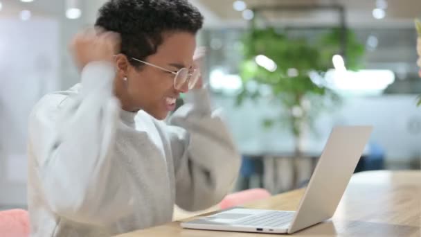 Взволнованная африканская женщина празднует успех на ноутбуке — стоковое видео
