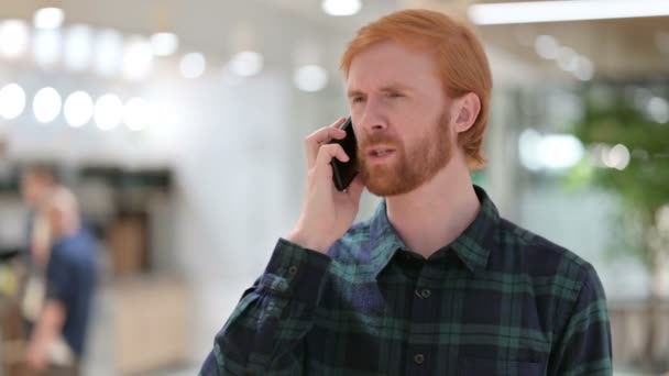 怒っているひげの赤毛の男の肖像｜スマートフォンで話している — ストック動画