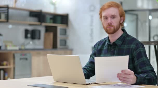 Barbe rousse homme avec ordinateur portable travaillant sur des documents — Video
