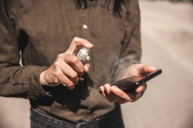 Kız telefon ekranına dezenfektan sıkıyor..