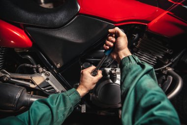 İngiliz anahtarlı, yakın çekim erkek eli. Tamirci garajda çalışıyor. Tamir servisi. Motosiklet tamiri. Birinci kişi görünümü