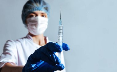 Doktor kız şırıngaya ilaçla bakıyor. Şırıngayı kapat.