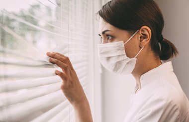 Doktor pencereden dışarı bakar. Kız doktor panjurlardan sokağa bakıyor.