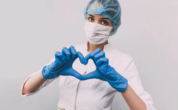 Maskeli genç doktor. Doktor bir kalp gösteriyor.