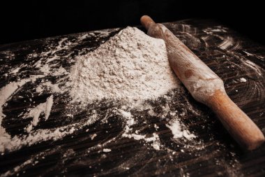 Masanın üzerinde bir parça un. Masada merdane var. Yakın plan fotoğraf.