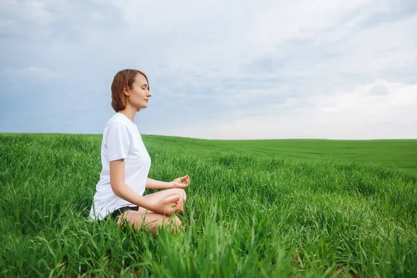 Young girl meditates in nature. Side view