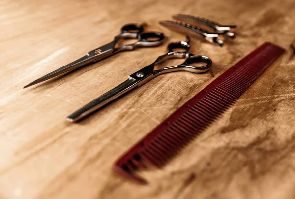 Hairdressing tools laid out on a wooden surface. Hairdressing comb and scissors