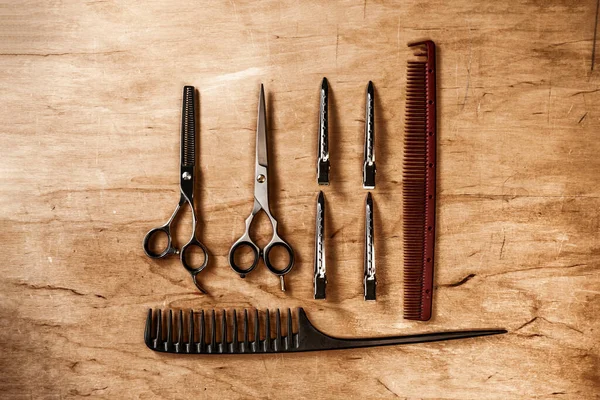 The hairdressing tool lies on a wooden board. Hairdressing combs and scissors
