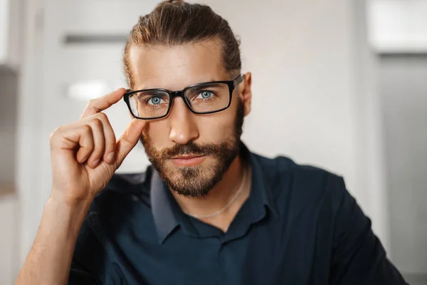 Genç bir adam gözlüklerini ayarlıyor. Gözlüklü genç adam. Yakın plan fotoğraf.