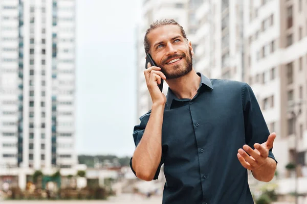 A young man is talking on the phone and smiling. Young man talking on the phone in the street