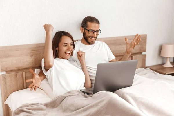 Glada Par Ligger Sängen Med Laptop Och Jublar — Stockfoto
