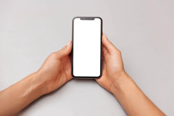 Beyaz ekranlı akıllı bir telefonun kadın ellerinde yakın plan çekimi. Masa arkasındaki cep telefonu