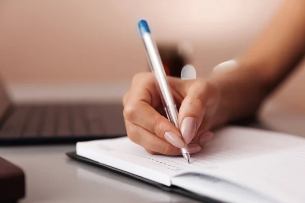 Woman makes a note in a notebook. Close up of a female hand making an entry in a notebook