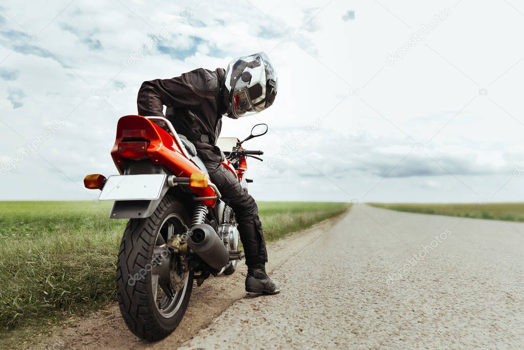 A biker inspects a sports bike that won't start. Man preparing for a motorcycle ride