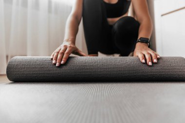 Kadın spor paspası açıyor, kız evde antrenmana hazırlanıyor.