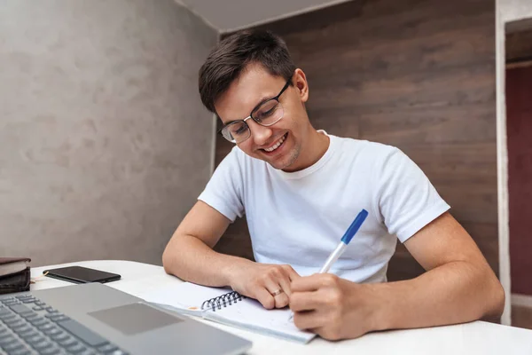 Joven Sonriente Hace Una Nota Cuaderno Tipo Trabaja Casa — Foto de Stock