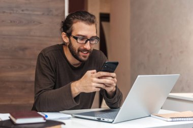 Mola sırasında cep telefonu kullanarak mesaj yazan mutlu adam.