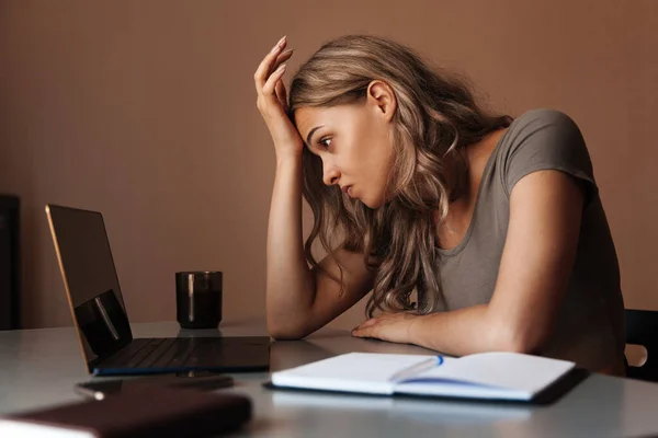 Tired woman looking at a laptop. Girl working at home on the computer