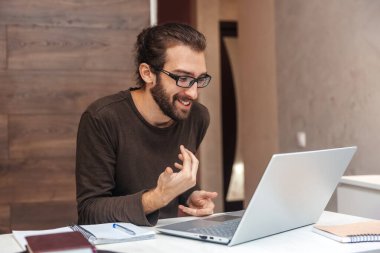 Karantina sırasında evde otururken bilgisayarla video bağlantısı kuran olumlu bir adam.