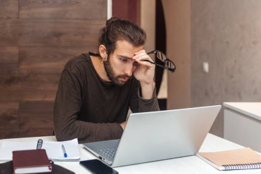 Yorgun bir programcının portresi. Bilgisayarda çalışan sakallı üzgün adam.