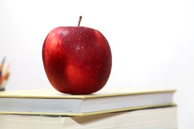 Masadaki okul malzemelerinin, Apple 'ın, masaüstündeki kitapların ve gözlüklerin birleşik resmi.