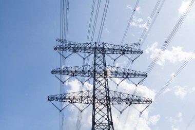 Mavi gökyüzünün altında yüksek voltajlı tel raf, enerji konsepti.