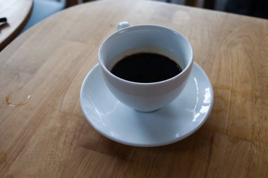 Bir fincan kahve, ahşap masa, üst manzara.