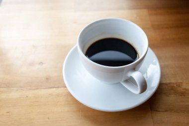 Bir fincan kahve, ahşap masa, üst manzara.