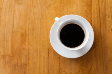 Bir fincan kahve, ahşap masa, üst manzara.