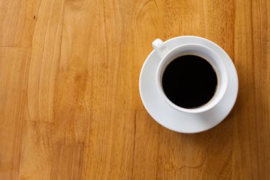 Bir fincan kahve, ahşap masa, üst manzara.