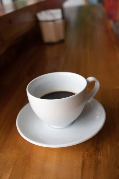 Bir fincan kahve, ahşap masa, üst manzara.