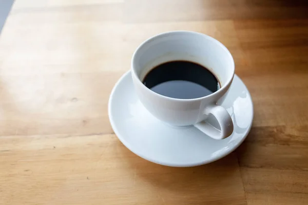 Bir fincan kahve, ahşap masa, üst manzara.