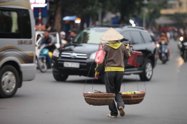 Hanoi başkenti, Vietnam - 12 Temmuz 2019 Hanoi, Vietnam 'daki sokak satıcıları. Taşralı kadın işlek bir sokakta taze çiçek satıyor.