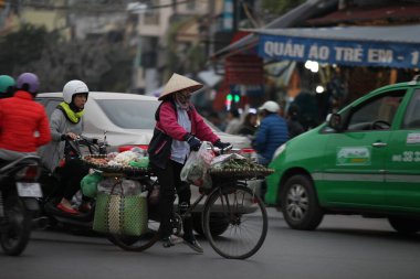 Hanoi başkenti, Vietnam - 12 Temmuz 2019 Hanoi, Vietnam 'daki sokak satıcıları. Taşralı kadın işlek bir sokakta taze çiçek satıyor.